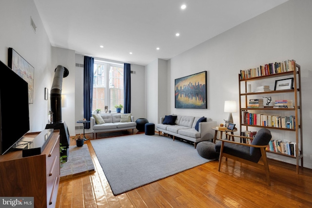 living room featuring recessed lighting, a wood stove, light wood-type flooring, and visible vents