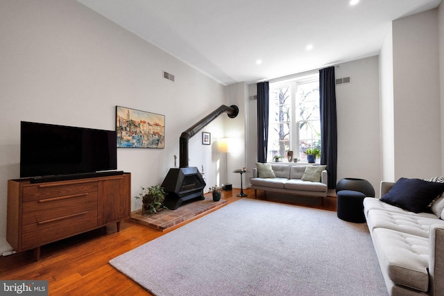 living room with visible vents, a wood stove, wood finished floors, and recessed lighting