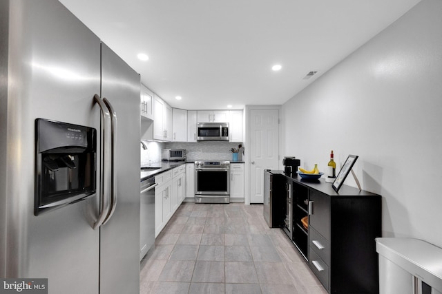 kitchen featuring white cabinets, backsplash, appliances with stainless steel finishes, and visible vents