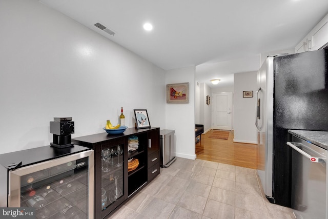 kitchen featuring white cabinets, appliances with stainless steel finishes, baseboards, wine cooler, and visible vents