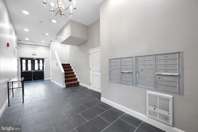 interior space with visible vents, mail area, a notable chandelier, and stairway