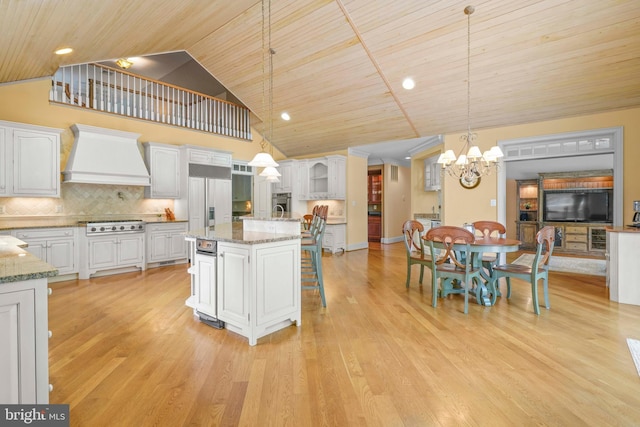 kitchen featuring a notable chandelier, a kitchen bar, white cabinetry, and premium range hood