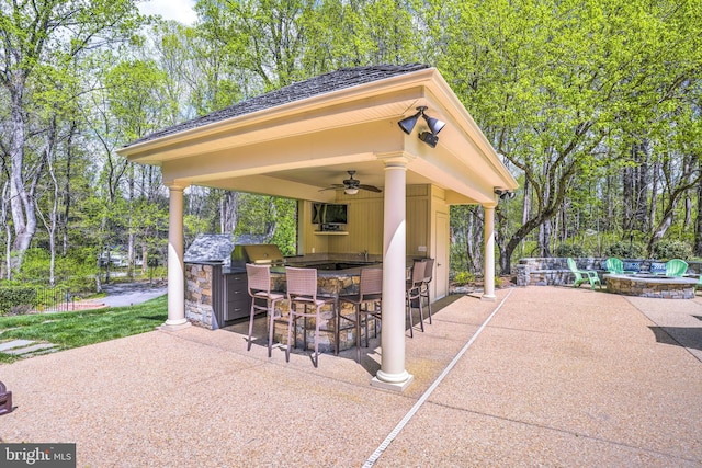 view of patio / terrace featuring a gazebo, outdoor dry bar, ceiling fan, area for grilling, and an outdoor fire pit