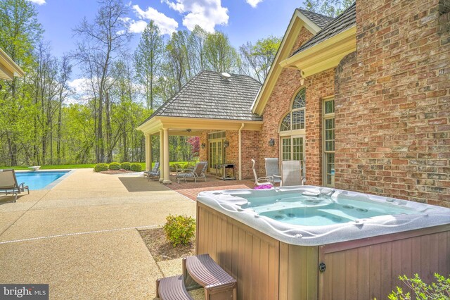 view of patio / terrace with an outdoor pool and a hot tub