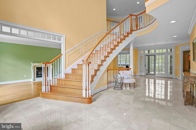 stairway with baseboards, crown molding, a towering ceiling, and recessed lighting