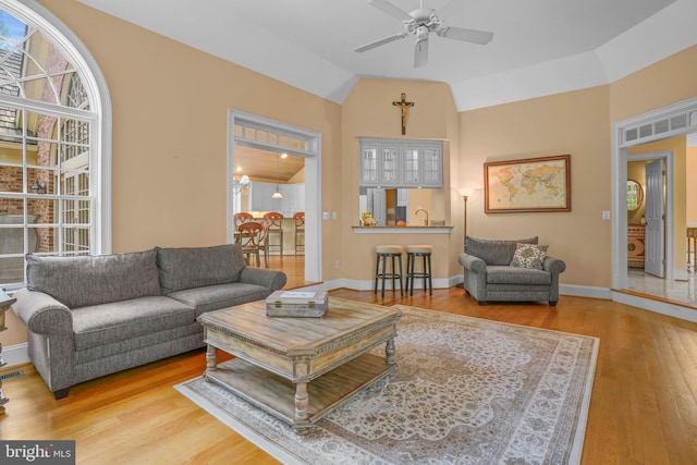 living area with wood finished floors, baseboards, ceiling fan, and plenty of natural light