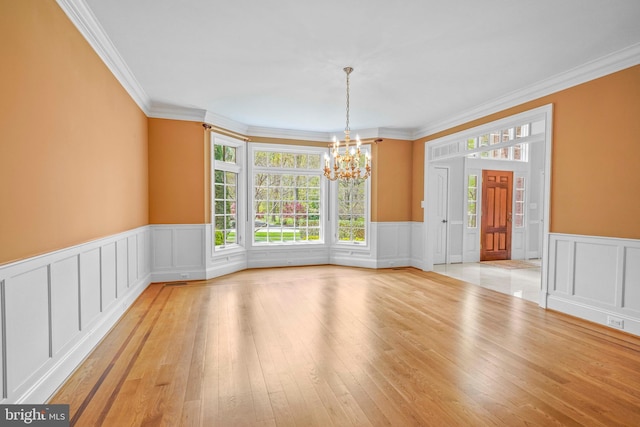 unfurnished dining area featuring plenty of natural light, light wood-style floors, a notable chandelier, and crown molding