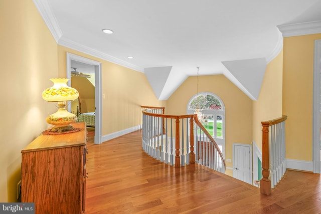 hall with light wood-style floors, an upstairs landing, and ornamental molding