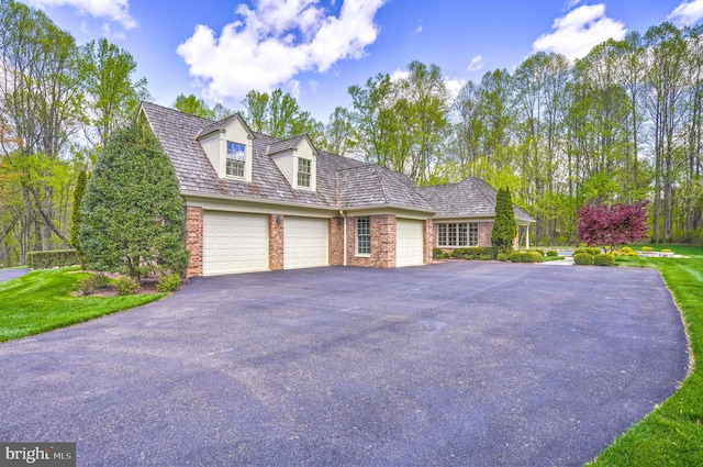 view of side of property featuring an attached garage, aphalt driveway, and brick siding
