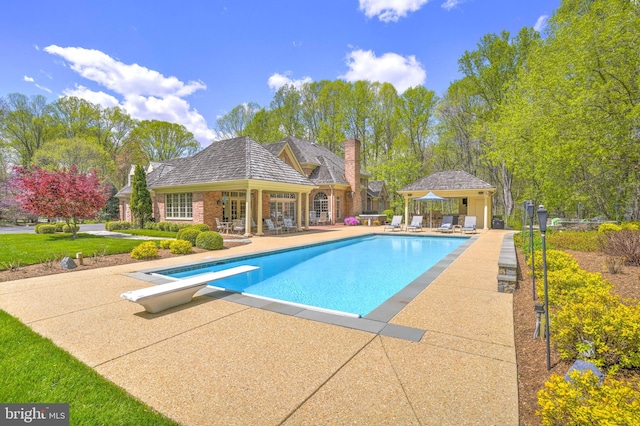 pool with french doors, an outbuilding, a storage structure, a patio area, and a diving board