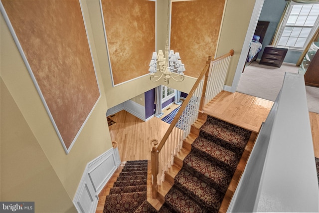 staircase featuring a chandelier, wood finished floors, and baseboards