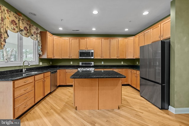 kitchen featuring a kitchen island, light wood-type flooring, a sink, and appliances with stainless steel finishes