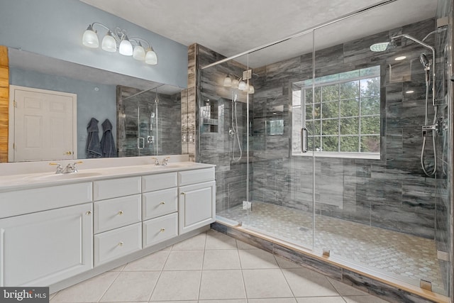 full bathroom featuring a shower stall, tile patterned floors, double vanity, and a sink