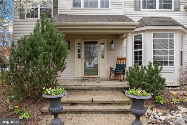 property entrance with a porch and roof with shingles