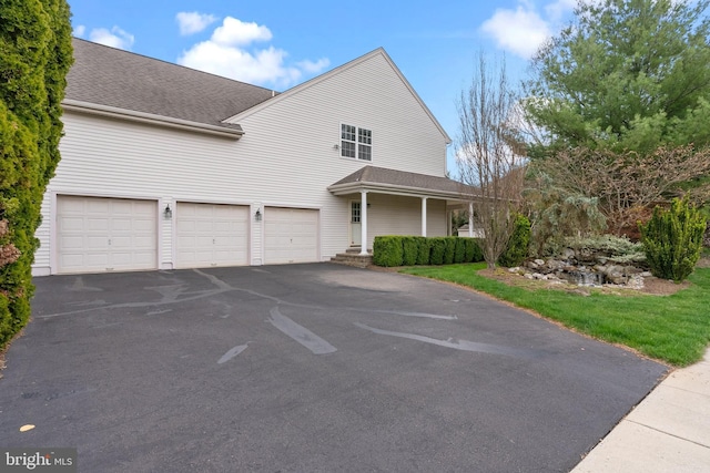 traditional-style house with an attached garage, a shingled roof, driveway, and a porch