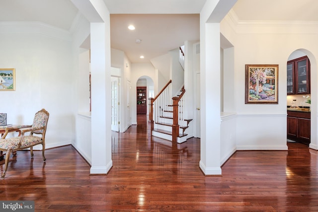 entrance foyer featuring arched walkways, ornamental molding, wood finished floors, and stairs