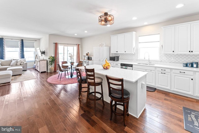 kitchen featuring appliances with stainless steel finishes, a breakfast bar, a sink, light countertops, and white cabinetry
