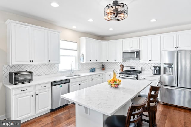 kitchen featuring a sink, a breakfast bar area, stainless steel appliances, white cabinetry, and a toaster