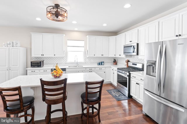 kitchen featuring a sink, tasteful backsplash, stainless steel appliances, and a kitchen bar