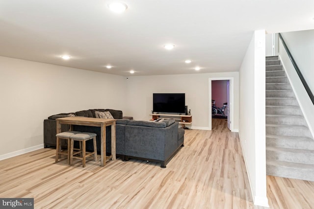 living room featuring baseboards, light wood-type flooring, and stairs