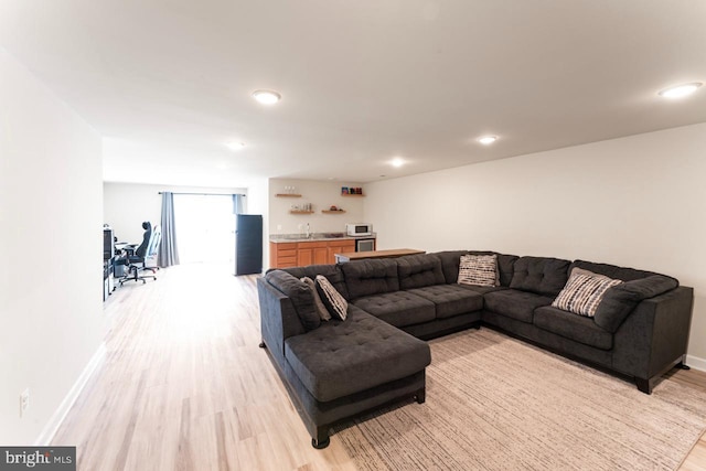 living area with indoor wet bar, recessed lighting, baseboards, and light wood-type flooring