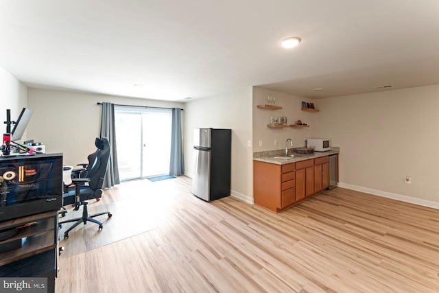 office with indoor wet bar, a sink, light wood-style flooring, and baseboards