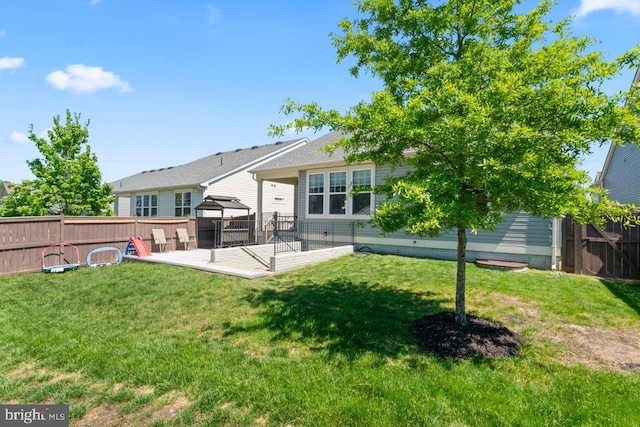 rear view of property with a fenced backyard, a gazebo, and a yard