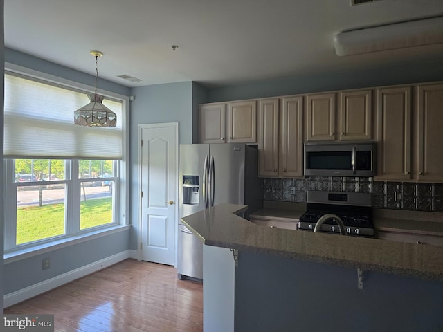2100 Ganton Grn Unit B-104, Woodstock, MD 21163 - kitchen featuring appliances with stainless steel finishes, decorative backsplash, light wood finished floors, hanging light fixtures, and baseboards