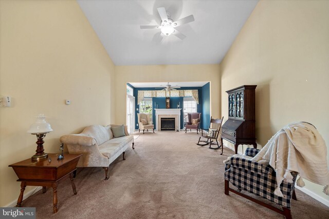 living area featuring carpet flooring, ceiling fan, a fireplace with flush hearth, and high vaulted ceiling
