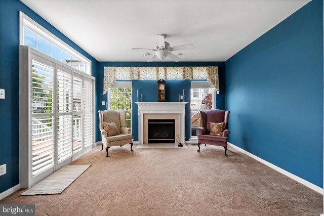 sitting room featuring ceiling fan, a fireplace with flush hearth, carpet floors, and baseboards