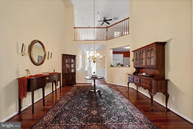 foyer featuring a high ceiling, dark wood finished floors, visible vents, baseboards, and ceiling fan with notable chandelier