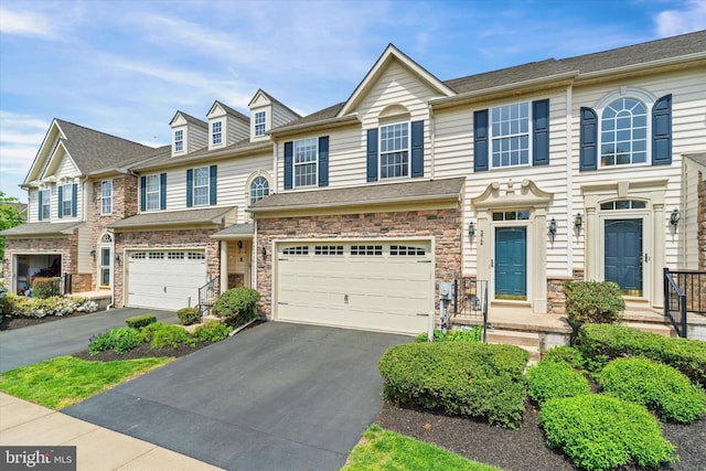 multi unit property featuring stone siding, aphalt driveway, and an attached garage