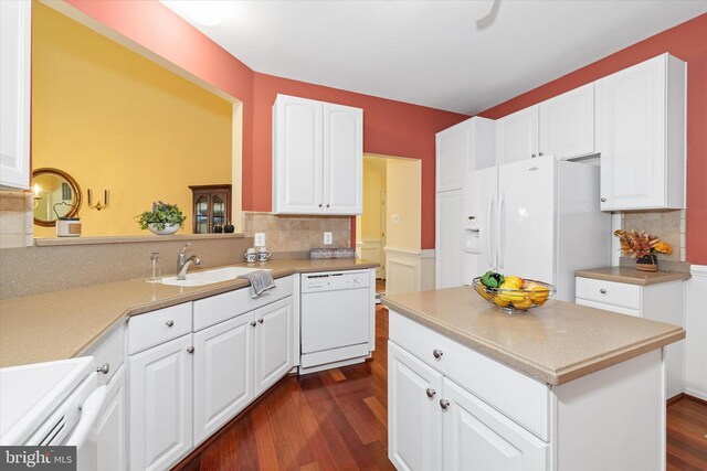 kitchen with white appliances, decorative backsplash, white cabinets, a sink, and dark wood-type flooring