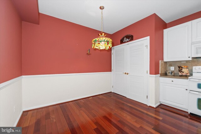 unfurnished dining area with dark wood finished floors and baseboards