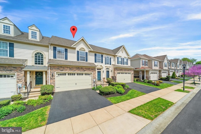 multi unit property with a garage, aphalt driveway, a residential view, and stone siding