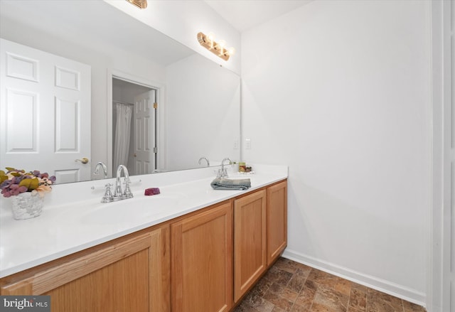 bathroom with baseboards, stone finish floor, and vanity