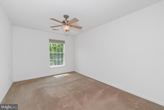 carpeted empty room featuring a ceiling fan, visible vents, and baseboards
