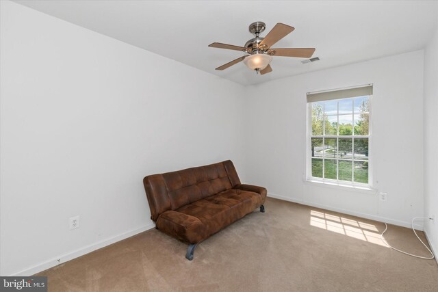 living area featuring baseboards, visible vents, ceiling fan, and carpet