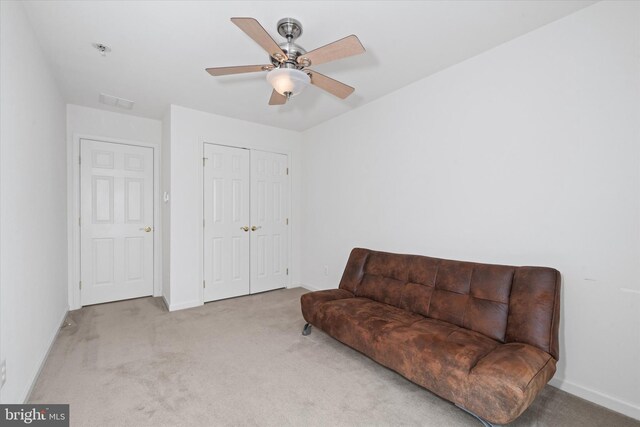 living area featuring baseboards, a ceiling fan, and carpet flooring
