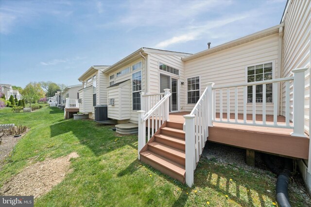 back of property with cooling unit, a wooden deck, a yard, and a residential view