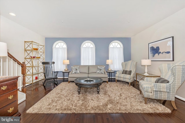 living area featuring baseboards, stairway, and dark wood-type flooring