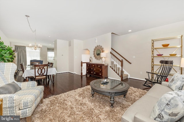 living area featuring wood finished floors, baseboards, a notable chandelier, and stairs