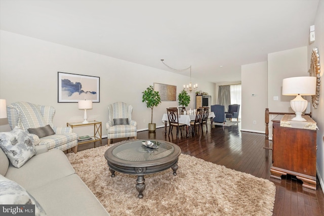 living room with baseboards, an inviting chandelier, and wood-type flooring
