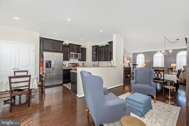 living area featuring recessed lighting, a notable chandelier, dark wood-style flooring, and baseboards