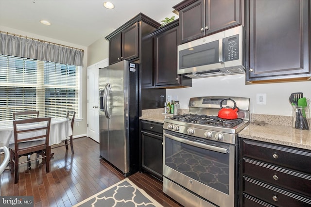 kitchen with light stone counters, dark wood-style flooring, stainless steel appliances, and dark brown cabinetry