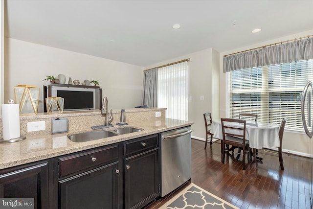 kitchen with a sink, baseboards, light stone countertops, dishwasher, and dark wood finished floors