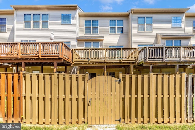 back of property with a wooden deck, fence, and a gate