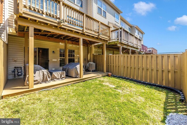 view of yard with a deck, central AC unit, and fence