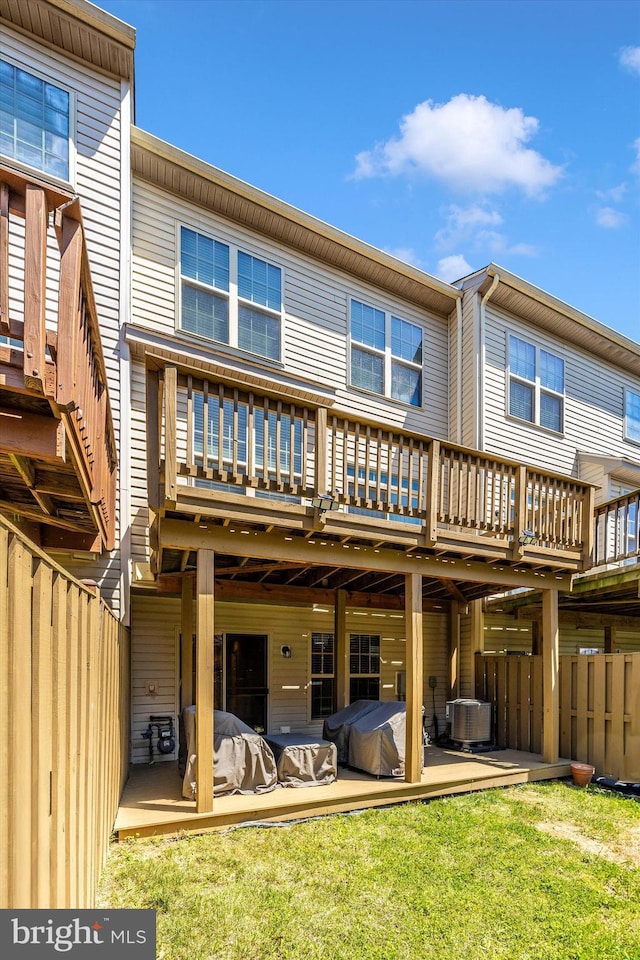 rear view of property with fence, a lawn, central air condition unit, and a wooden deck