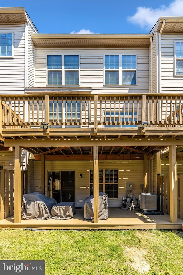 rear view of property with a deck, cooling unit, and a lawn